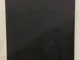un lave-vaisselle noir posé sur un sol vert, à côté d'un mur blanc