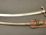 an old dagger with a leather sheath on a gray surface