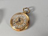 a gold pocket watch with roman numerals on it