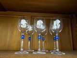 four wine glasses are lined up on a shelf in a cabinet