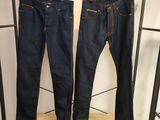 deux paires de jeans suspendues à un portant dans un magasin de vêtements