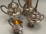 four pieces of silver tea and coffee set on a table