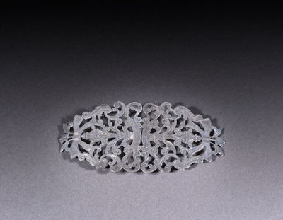 an antique silver broochle on a gray surface