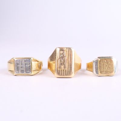 three gold and silver rings on a white surface with a white background