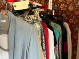 a lot of clothes hanging on a rail in a closet