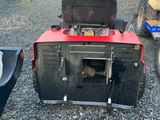 an image of a red and black lawn mower parked in a parking lot