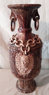 un vase marron orné de chaînes, posé sur une table