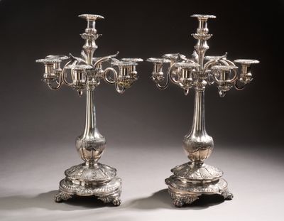 pair of silver plated candelabs with candles on stands