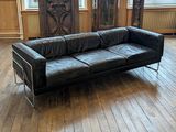 un canapé en cuir noir posé sur un parquet dans un salon