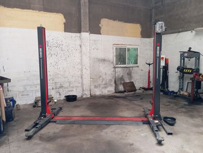 une photo d'un garage avec deux ponts élévateurs au milieu
