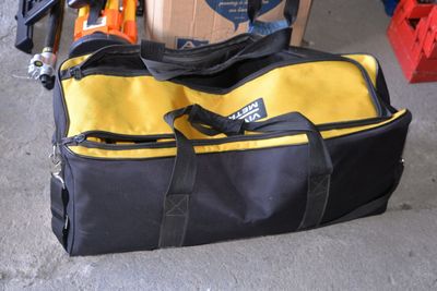 un sac de voyage jaune et noir posé par terre