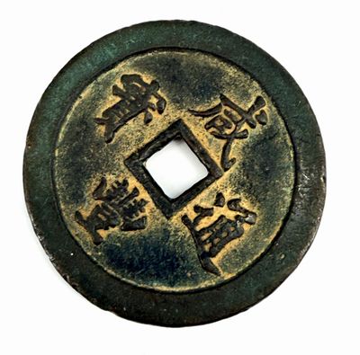 an old chinese coin with chinese writing on it on a white surface