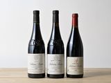 trois bouteilles de vin sont posées les unes à côté des autres sur une table en bois