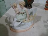 une figurine représentant deux fillettes assises sur un coquillage