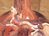 a brown and white vase with a lizard on it