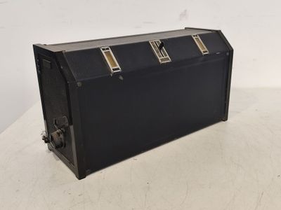 une vieille valise noire posée sur une table blanche