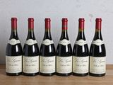 six bottles of red wine lined up on a wooden table