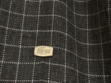 a close up of a black and white checkered suit with a gold button