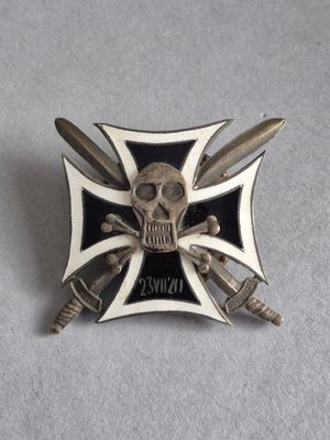 une broche argentée et noire sur laquelle figurent un crâne et des épées