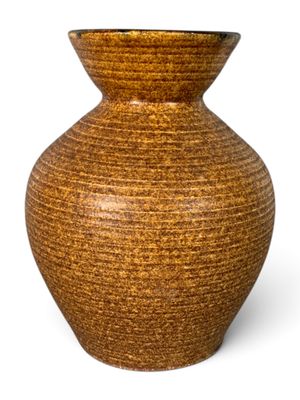 un vase brun posé sur une surface blanche