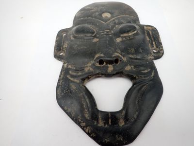 une image représentant un masque noir dont la bouche a la forme d'une tête de singe