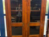 une grande armoire en bois avec des portes vitrées dans la pièce