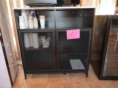 a black cabinet with a pink sticker on it in a kitchen