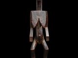 une statue en bois représentant un homme debout au sommet d'un rocher
