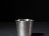 a silver cup sitting on top of a table next to a black background