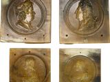 a set of four bronze plaques depicting the head of a man and a woman
