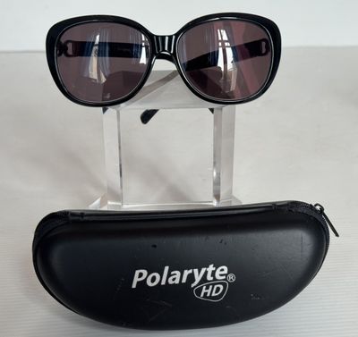 une paire de lunettes de soleil Polarvitee dans un étui noir posé sur une surface blanche
