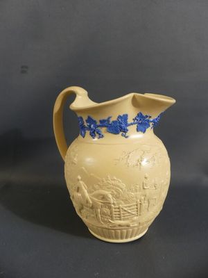 cream colored pitcher with blue flowers on it sitting on a black surface