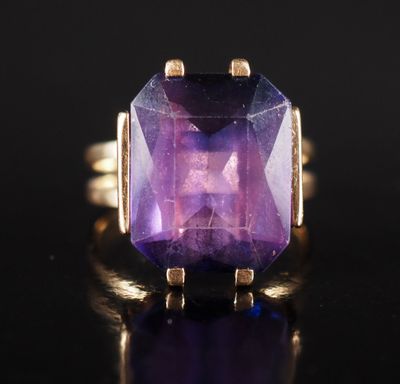un gros plan d'une bague en pierre violette posée sur une surface noire
