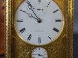 a gold clock with roman numerals on the face