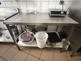 une cuisine avec une table en inox et des seaux posés par terre