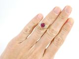woman ' s hand with a diamond and ruby ring on it ' s finger