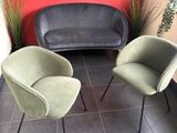 two chairs and a couch in a room with a red wall