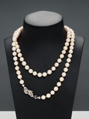 a white pearl necklace with a silver clasp on a mannequin