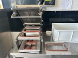 several trays of food sit on top of a table in a kitchen