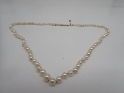 un collier de perles blanches avec un fermoir en or sur fond blanc
