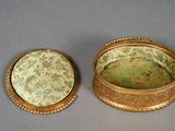 pair of gold - plated boxes with floral designs on them on a gray surface