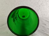 a green glass vase with a black rim on a white surface