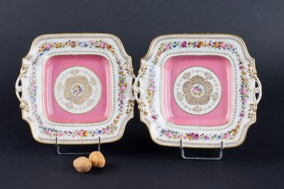 une paire d'assiettes roses et dorées ornées de motifs floraux