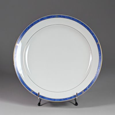 une assiette bleue et blanche bordée d'or, posée sur un socle