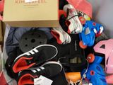 a box full of skates and skateboard gear on the floor