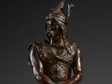 bronze statue of a man with a hat on his head holding a cane
