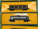 trois wagons de train miniature dans une boîte verte, posés sur une table