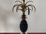 a black and gold vase with a plant on top of it
