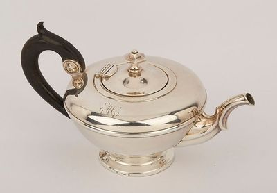 an antique silver teapot with a black handle on a white surface