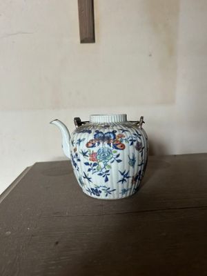 une théière posée sur une table, avec une croix en arrière-plan